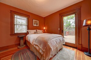 A bedroom with a bed, a bedside table, a lamp, and a window with blinds. - Historic Craftsman - Pet Friendly - Sleeps 6 (Long Beach)