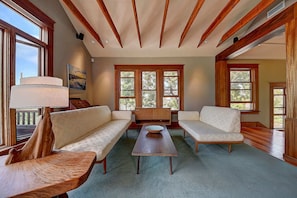 A spacious living room with a wooden ceiling, large windows, and a central coffee table. - Historic Craftsman - Pet Friendly - Sleeps 6 (Long Beach)