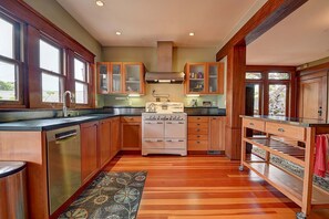 A kitchen with wooden cabinets, a stainless steel dishwasher, a double oven, and a built-in stove. - Historic Craftsman - Pet Friendly - Sleeps 6 (Long Beach)