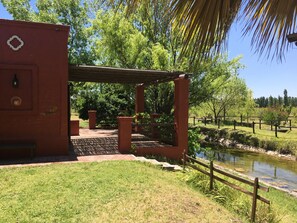 A red building with a pergola entrance, a small pond, and a wooden fence.