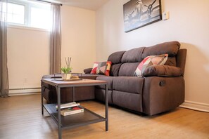 Ein Wohnzimmer mit einem braunen Sofa, einem kleinen Beistelltisch und einem gerahmten Bild an der Wand.