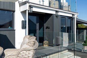 A modern building with a glass entrance, outdoor seating, and a clear view of the sky. - Vitamin Sea - Swimming Pool, Hot Tub, Sea Views (Saundersfoot)