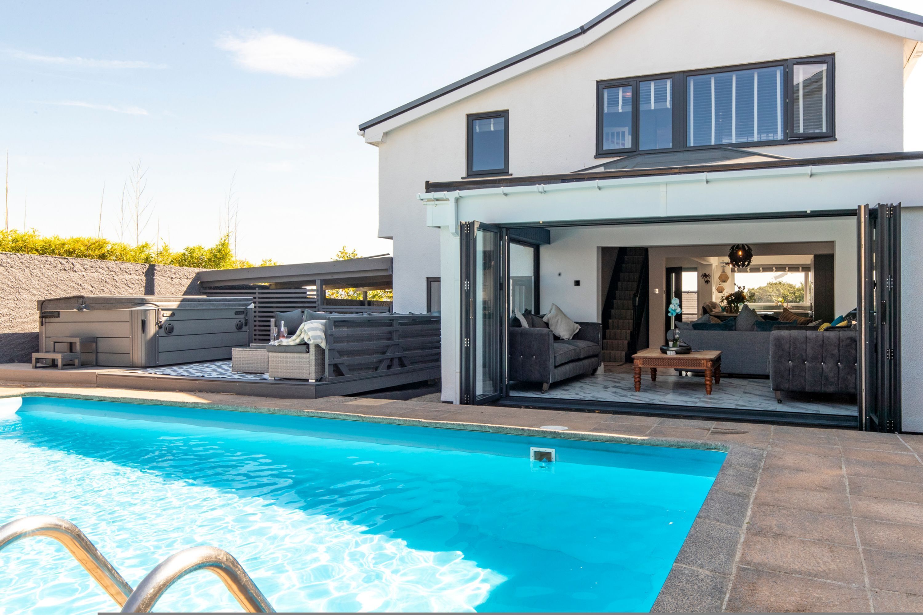 A modern house with a swimming pool, outdoor seating, and a glass-enclosed patio.