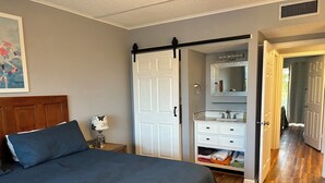 Une chambre à coucher comprenant un lit, une table de chevet, une commode et un dressing.