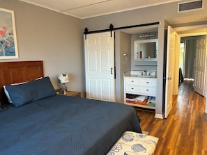 A bedroom with a bed, a nightstand, a dresser, and a walk-in closet. - Beachfront condo with direct pool & ocean view on Crescent Beach (St. Augustine)