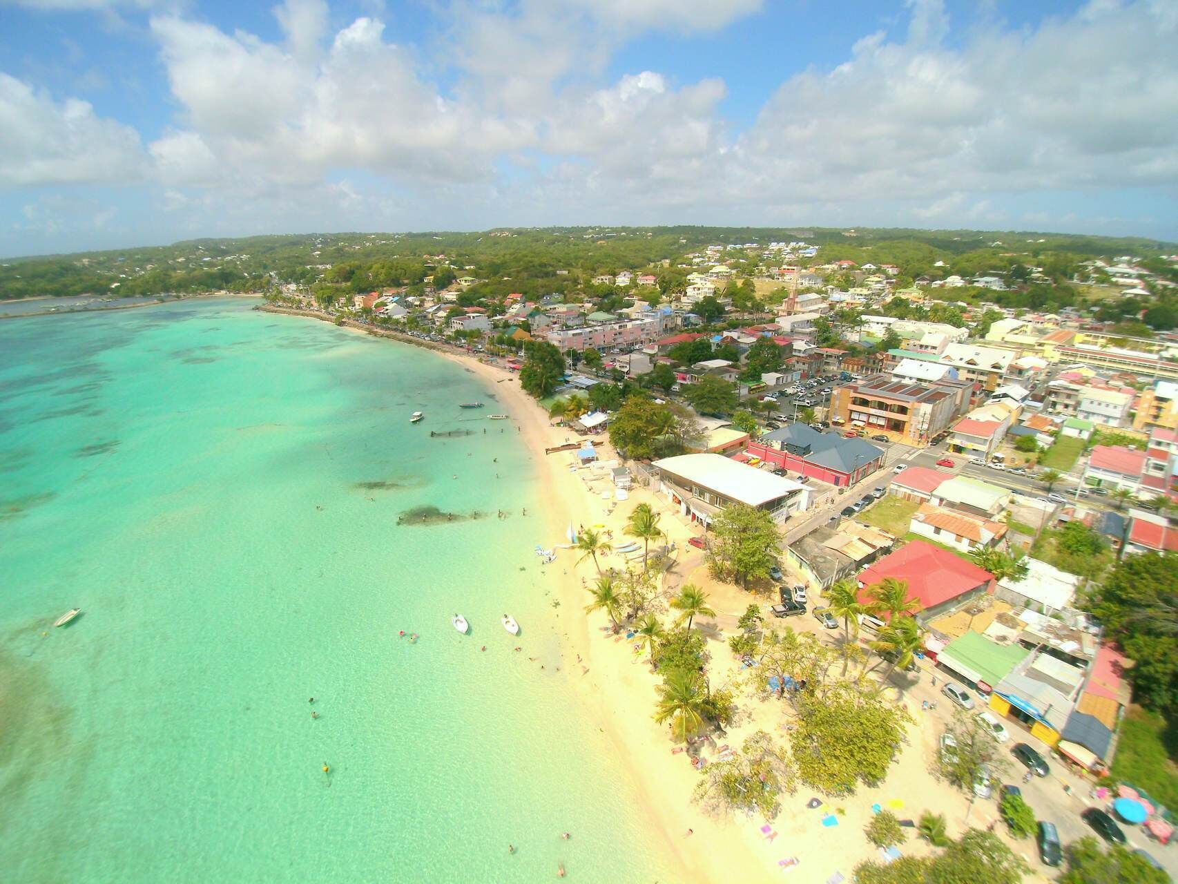 A coastal town with a beach, buildings, and clear turquoise waters.