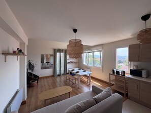 A modern living space with a dining area, kitchen, and a large window offering a view of the outdoors. - Quiet apartment with a view of Hendaye Bay (Hendaye)
