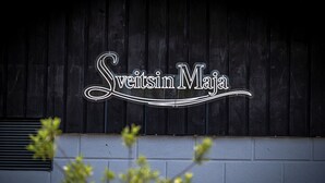 Un letrero con el texto 'Sweetsin MaJa' sobre un fondo de madera oscura.