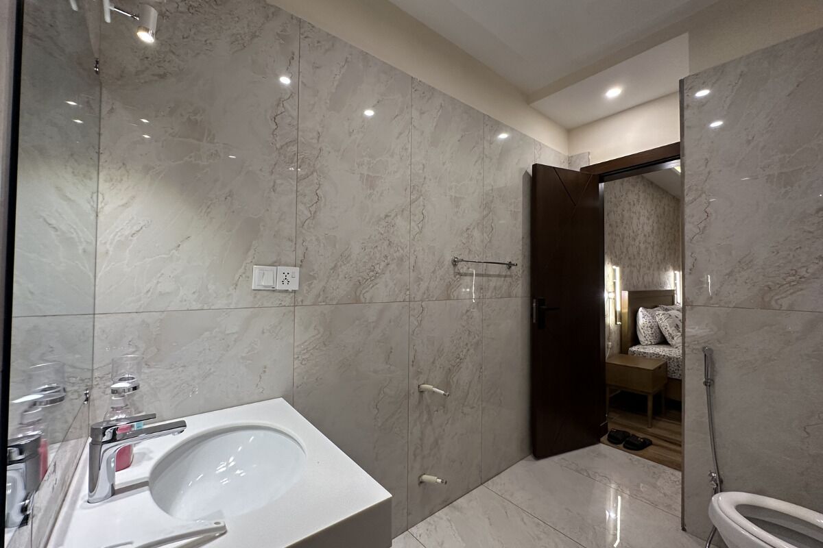 A modern bathroom with a large white sink, a toilet, and a shower area.