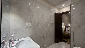 A modern bathroom with a large white sink, a toilet, and a shower area.