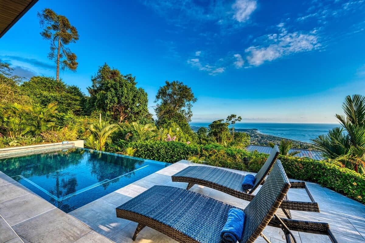 Un espace aménagé au bord de la piscine, avec des chaises longues et une vue sur l’océan.