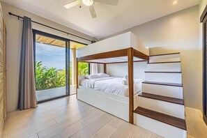 Ein modernes Schlafzimmer mit Bett, Einbauschränken und Blick auf Grünflächen.