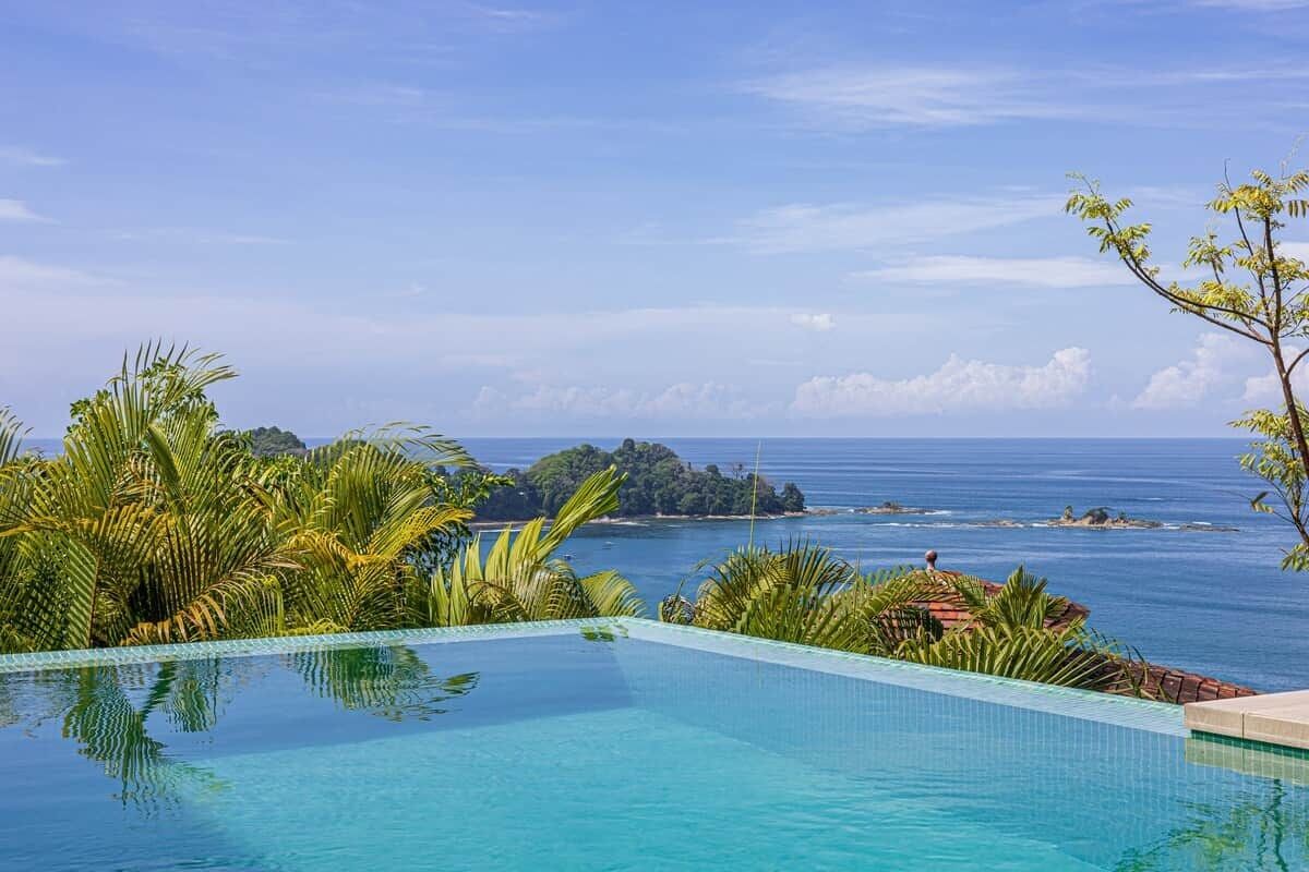 A clear blue pool with a view of the sea and a small island.