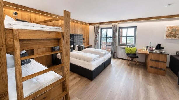 Een kamer met een stapelbed, een bureau en een stoel.
