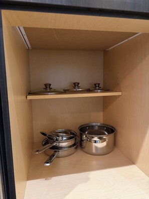 Eine Küchenschrank mit zwei Edelstahltöpfen und einem Löffel.