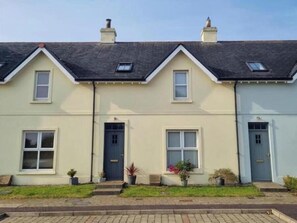 A row of terraced houses with a front door, windows, and small garden areas. - 4 Bed Eco-Retreat With Parking Near Bushmills (Bushmills)