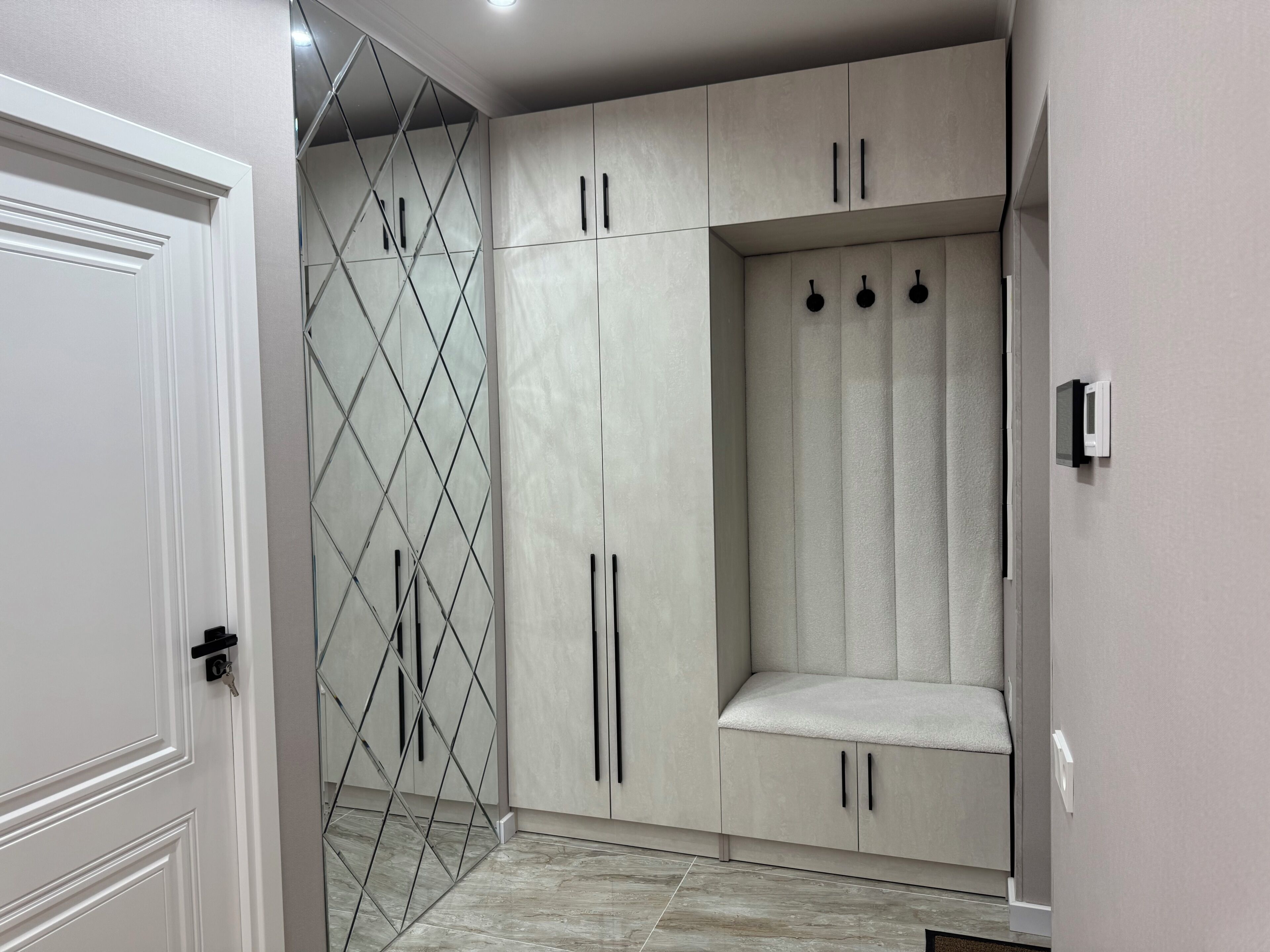 Un dressing accessible sans porte, doté d’une armoire à miroir, d’un banc et d’un porte-manteau.