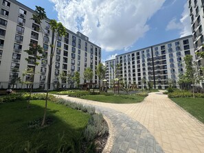 Ein Mehrfamilienhaus mit gepflastertem Weg und Grünflächen.