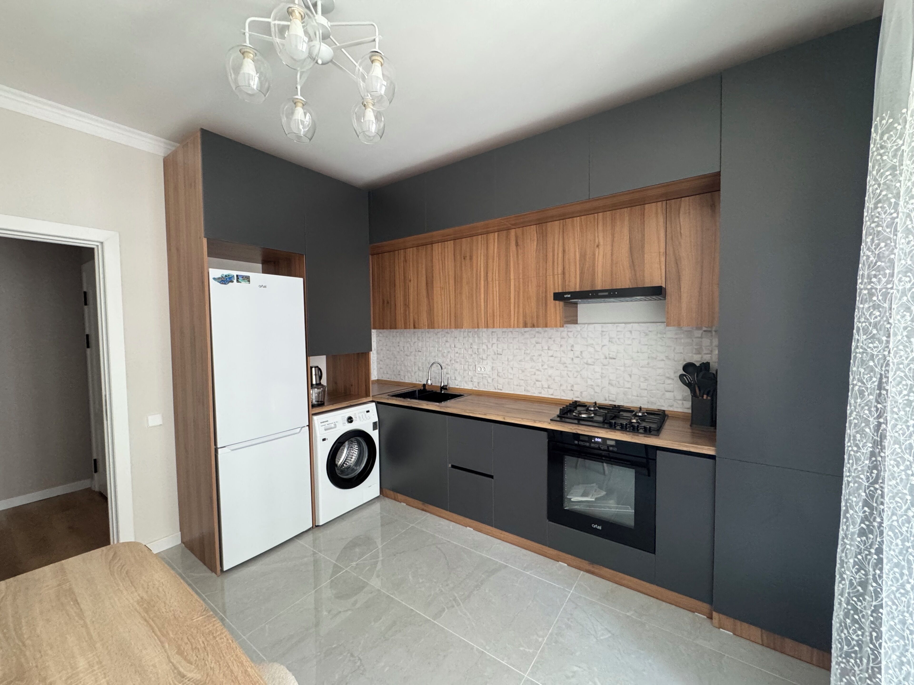 A modern kitchen with a built-in washer, a stove, and a sink.