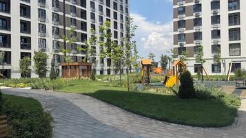 Ein Wohngebäude mit mehreren Balkonen, einem Spielplatz und einem gepflasterten Weg.
