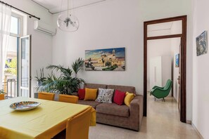 Ein Wohnzimmer mit einer Couch, einem Esstisch und einem Gemälde eines Gebäudes.