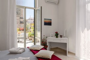 A hotel room with a bed, a desk, a window, and a view of the outside. - Casa Ninetta - Terrace near Central Station (Palermo)