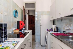 A compact kitchen with a washing machine, a coffee machine, and a small sink. - Casa Ninetta - Terrace near Central Station (Palermo)