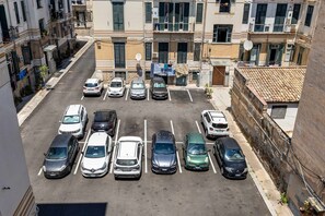 A parking lot with multiple cars parked in a row, surrounded by buildings with balconies and windows. - Casa Ninetta - Terrace near Central Station (Palermo)