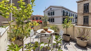 A terrace with outdoor seating, potted plants, and a view of historic buildings. - Casa Ninetta - Terrace near Central Station (Palermo)