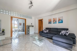 Ein stilvolles Wohnzimmer mit einer Couch, einem Glastisch und einem Essbereich mit Stühlen und einem Tisch.