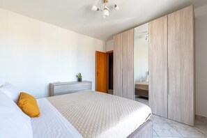 A bedroom with a bed, a bedside table with a plant, and a wardrobe. - Spacious Apartment close to the Beach-Isola Summer (Isola delle Femmine)