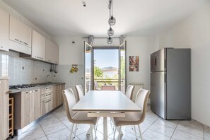 Eine moderne Küche mit Essbereich, einem Edelstahlkühlschrank und Blick durch die offene Tür.