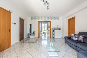 Uma sala de estar moderna com uma mesa de centro de vidro, um sofá e um espaço de jantar com mesa e cadeiras.