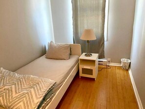 A bedroom with a bed, a nightstand, a lamp, and a window with curtains. - Charming 4½-room apartment near the Finnish Spa | Relaxation and business stays (Laval)