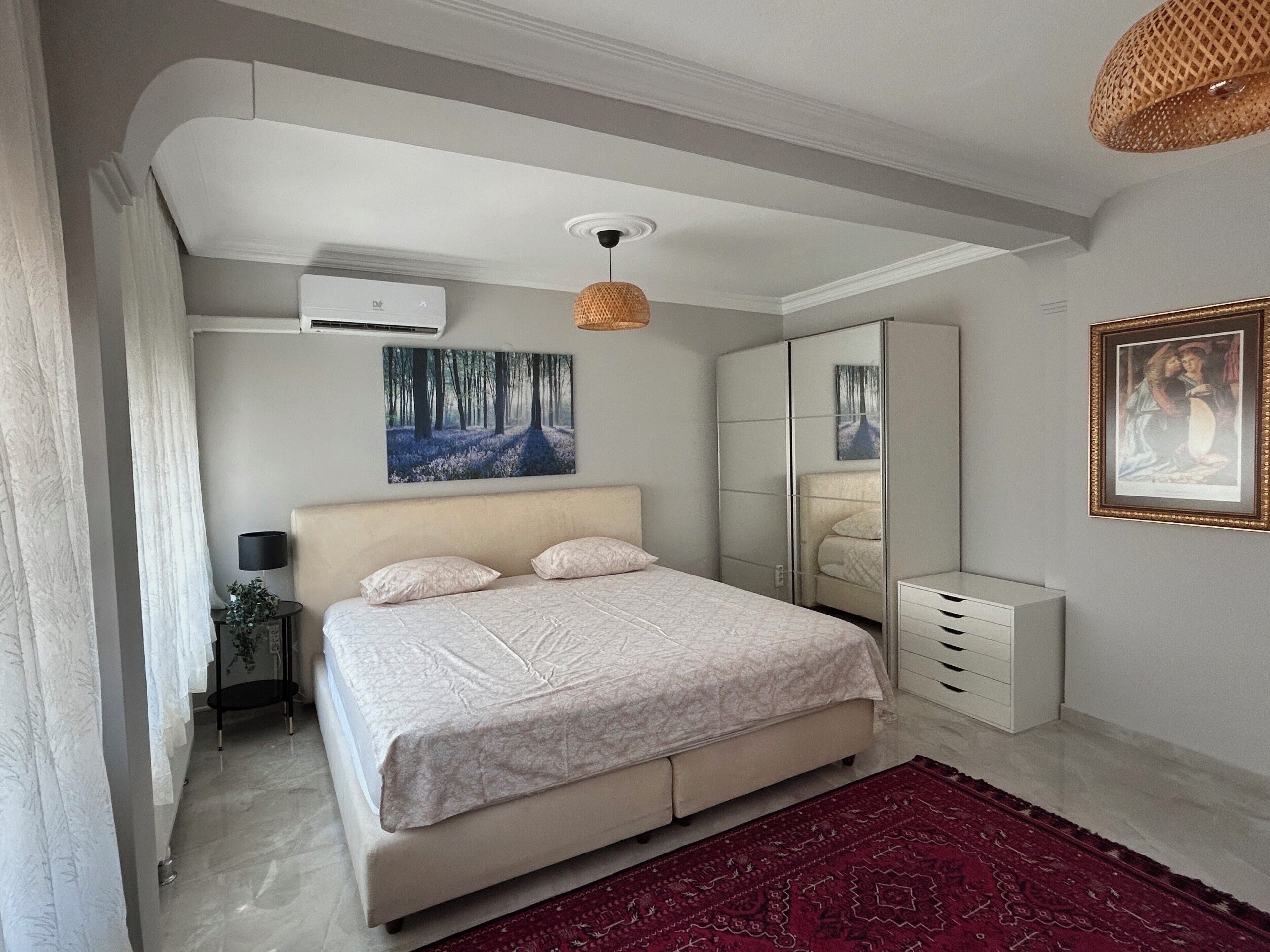 A bedroom with a bed, a mirror, a wardrobe, and a painting on the wall.
