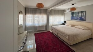 A modern bedroom with a large bed, a red rug, and a painting on the wall. - Renovated comfy apartment with unique sea view (Konak)