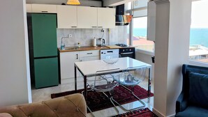 A compact kitchen with a dining area, a view of the sea, and a cozy seating arrangement. - Renovated comfy apartment with unique sea view (Konak)