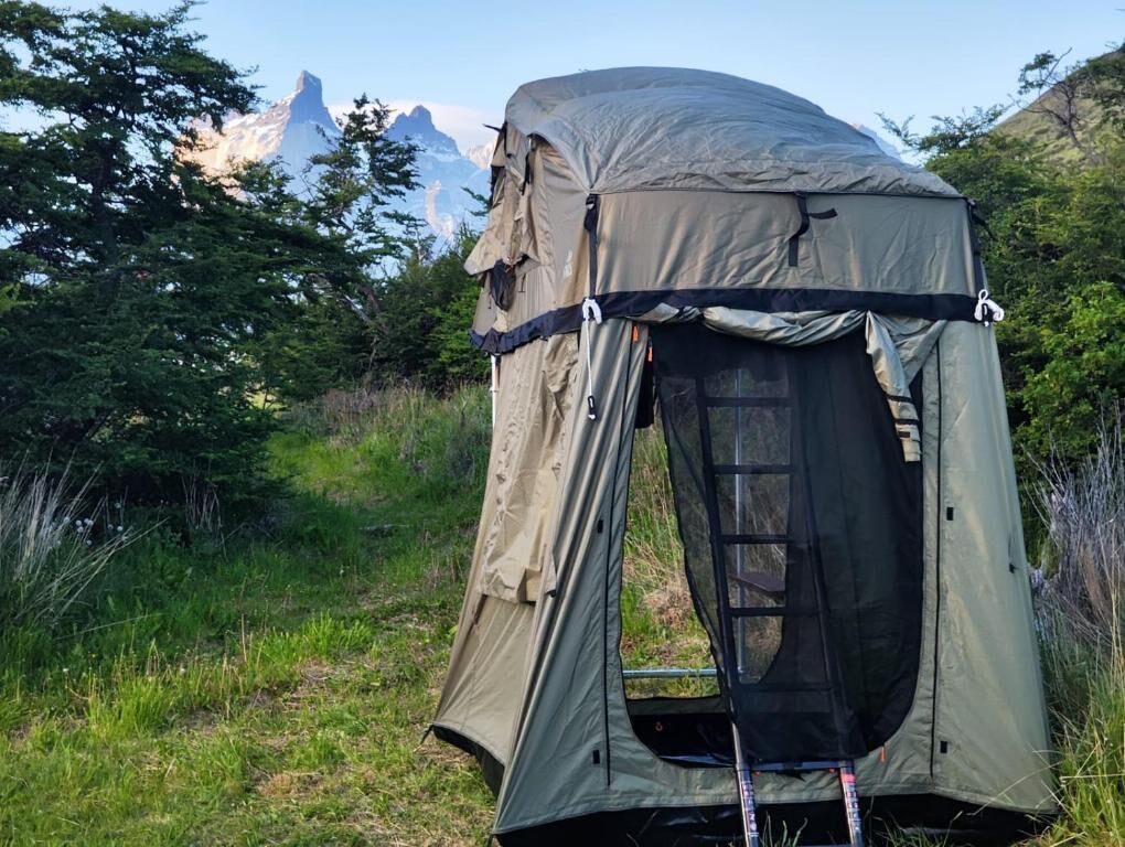 A tent set up in a natural environment with mountains in the background.