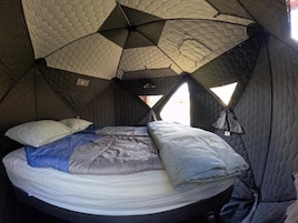 Una carpa con una cama, almohadas y un edredón.