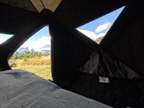 A tent with a view of mountains and a car in the background. - Yellow Plum Camp Pehoé (Torres del Paine)
