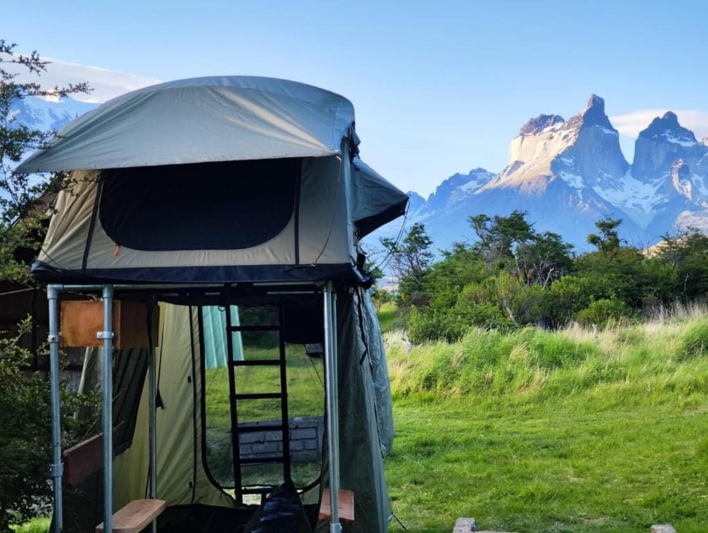A tent set up in a grassy area with a mountainous backdrop.