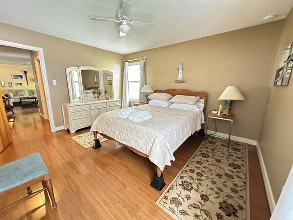A bedroom with a bed, dresser, mirror, and a ceiling fan.