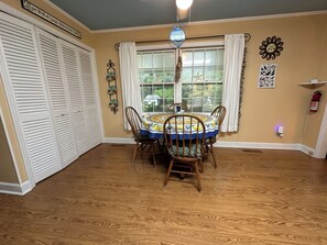 A dining area with a wooden table, chairs, and a window with curtains.