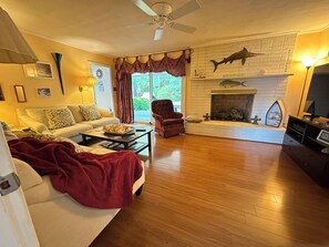 A living room with a white sofa, a red blanket, a coffee table, a fireplace with a fish decoration, and a television on a stand.