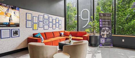 A modern lobby with a large window, a seating area with a sofa and chairs, a coffee table, and a QR code stand for ride booking.
