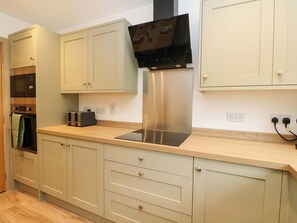 A kitchen with light-colored cabinets, a stainless steel range hood, a microwave, and a toaster. - Nevis Bridge House (Fort William)