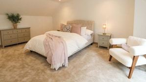 A bedroom with a bed, bedside tables, a chair, a lamp, and a plant. - Nevis Bridge House (Fort William)