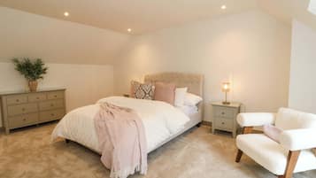 A bedroom with a bed, bedside tables, a chair, a lamp, and a plant.
