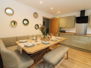 Un comedor con una mesa preparada para cuatro personas, rodeada por un sofá y dos sillones.
