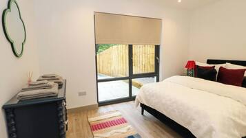 A bedroom with a bed, a nightstand, a mirror, a window, and a door.